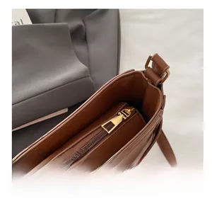 Detailed macro view of the smooth gold-tone zipper closure on the brown leather shoulder bag
