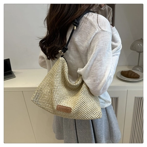 Detail of beige woven straw bag with black strap and leather fashion label decoration