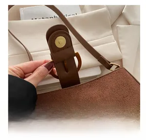 Detailed view of the magnetic hardware buckle on a brown suede crossbody small square bag