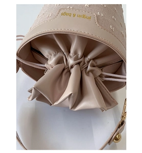 Détail du sac seau en toile beige avec broderie florale et cordon en cuir