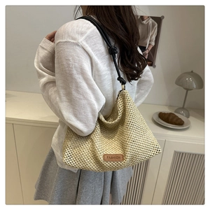 Detailed close-up of beige woven straw bag with FASHION leather tag and black rope handle