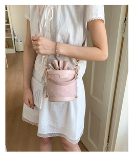 Detailed view of pink drawstring bucket bag with ruffles and metallic hardware