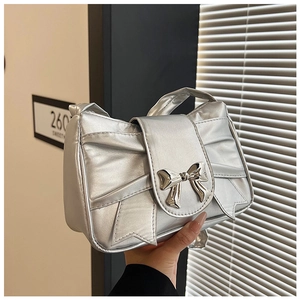 Close-up of metallic silver handbag with bow design and shiny metal buckle detail