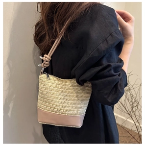 Detail of beige woven bucket bag with pink leather base and unique knotted shoulder strap