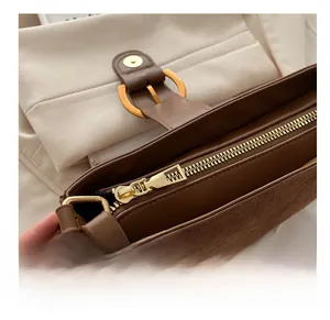 Close-up of smooth golden metal zipper and textured brown leather on underarm bag