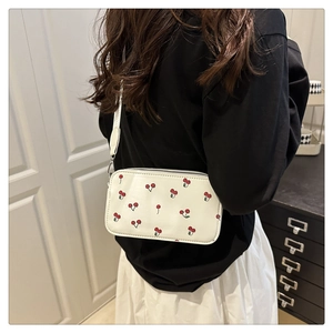 Detail view of a white shoulder bag with cute cherry prints and slim shoulder strap