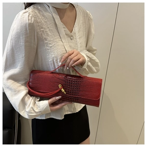 Detail of red crocodile pattern evening clutch with golden twist lock and slim handle