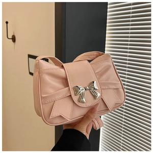 Detail of pink bow handbag featuring a stylish silver metal buckle and soft fabric texture