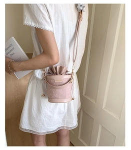 Detail of elegant drawstring bucket bag in dusty rose with adjustable shoulder strap