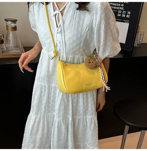 Detail of yellow faux leather crossbody bag with cute teddy bear and ribbon accessory
