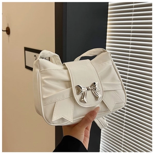 Close-up of a white pleated handbag with a silver bow clasp and elegant chain strap