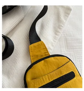 Détail du sac bandoulière en nylon jaune montrant la texture résistante et la fermeture