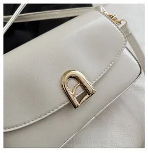 Détail d'un sac crème montrant la texture du cuir plissé et le fermoir doré en métal