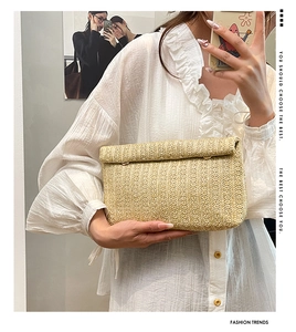 Detail of woven straw clutch bag showing natural fiber texture and golden buckle fastener