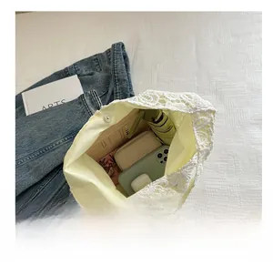 Grand sac fourre-tout en dentelle blanche contenant téléphone, parapluie et portefeuille