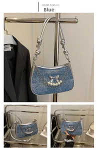 Detailed view of blue denim shoulder bag featuring silver butterfly bow and pearl chains