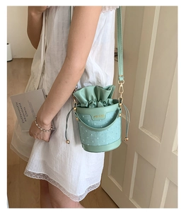 Detail of mint green bucket bag with embroidered polka dots and drawstring closure