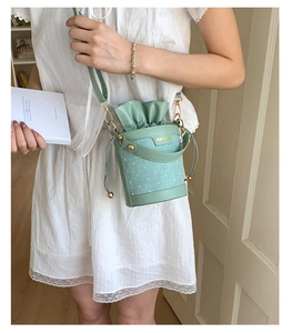 Detail of mint green bucket bag featuring embroidered dots and drawstring closure