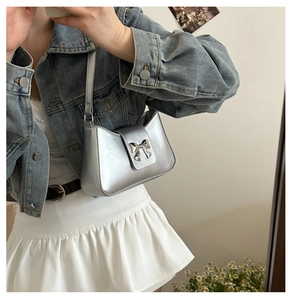 Silver metallic baguette shoulder bag with a metal bow detail shown in a casual outfit