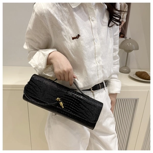 Detail of elegant black crocodile embossed leather handbag with golden metal twist lock
