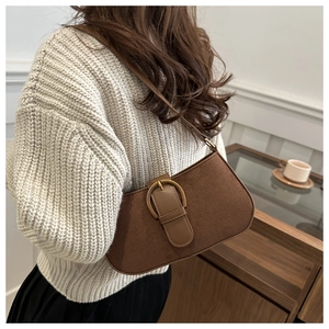 Detail of dark brown retro underarm bag with a prominent golden ring buckle and suede texture