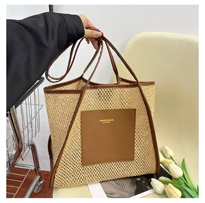 Detail of woven straw tote bag featuring brown leather trim and fashion embossed front pocket