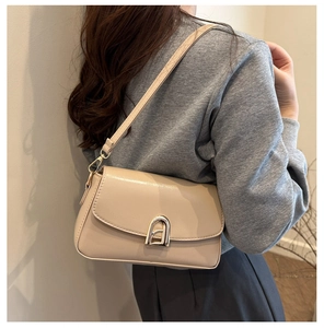 Detail view of beige crossbody bag with golden arch twist lock and fine leather texture