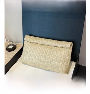 Detail of beige woven clutch bag with gold metal rings inside premium gift box