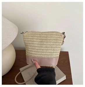 Details einer beige Stroh-Eimertasche mit rosa Lederboden und Umhängeriemen