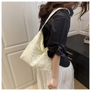 Détail de la dentelle florale évidée sur un grand sac cabas en coton beige