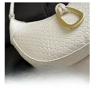 Macro detail of white woven leather texture and elegant gold D-ring buckle of this handbag