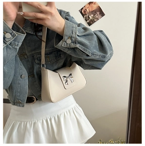 Détail du sac sous l'aisselle en cuir blanc crème avec boucle noeud argenté poli