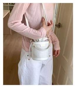 Detailed view of a white bucket bag with drawstring liner and textured synthetic leather