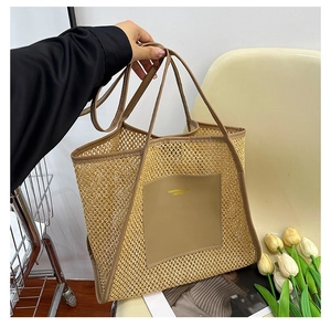 Close-up of woven tote bag with brown leather handles and gold brand lettering on the front patch