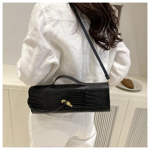 Detail of black crocodile texture leather crossbody bag with elegant gold hardware