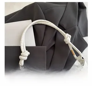 Detail of white woven leather shoulder strap with knot design and gold metal hardware