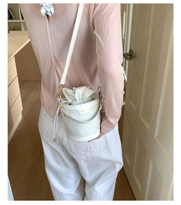 Detail showing white bucket bag with textured leather and drawstring closure