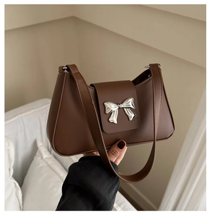 Detailed view of brown retro underarm bag featuring a metallic silver butterfly clasp