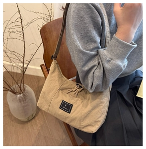 Detail van kaki nylon halvemaantas met geknoopte ritssluiting en merklabel accenten