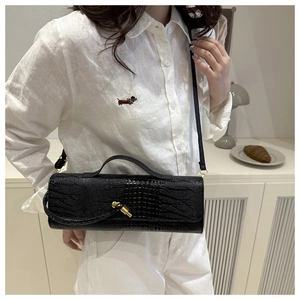 Chic black crocodile embossed crossbody bag with gold turn-lock worn by a model