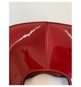 Détail macro d'un sac à main en cuir verni rouge brillant avec surpiqûres précises
