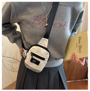 Détail d'un sac bandoulière blanc en nylon avec une sangle réglable de couleur noire