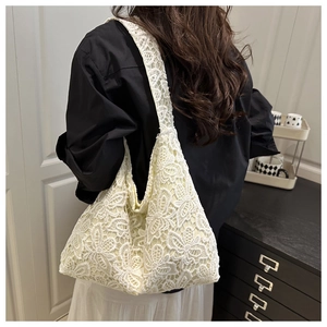 Détail d'un sac cabas en dentelle florale blanche porté par un mannequin en intérieur
