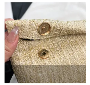 Detailed macro view of the gold magnetic closure on a beige woven straw handbag