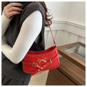 Detail of red leather shoulder bag with gold metal bow buckle shown on a model