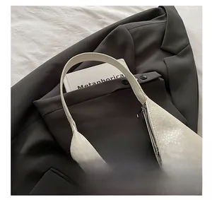 Detail of cream faux snake texture tote bag on grey blazer with fashion accessories