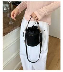 Detail of black drawstring bucket bag with polka dot texture and gold hardware