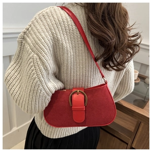 Detail of red suede underarm bag with vintage metal buckle and glossy leather trim