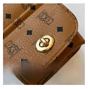 Détail d'un sac en cuir marron avec motif d'ours et fermoir rotatif en métal doré chic