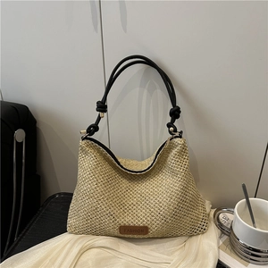 Minimalist woven straw shoulder bag with black knotted straps and leather label detail